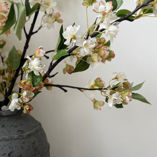 Decorative arrangement of flowers in a textured vase on a surface with a neutral background