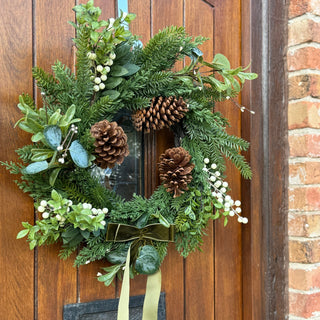 Green wreath with pinecones and berries on a wooden door
