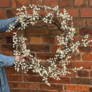 Person holding a decorative wreath against a brick wall