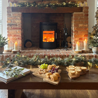Cozy living room with a lit fireplace, decorative garland, and festive table setting.