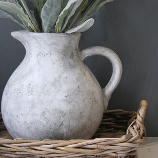 Grey stone jug in basket with flowers