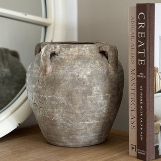 Vintage-style vase on a wooden surface with a book titled 'Create' in the background.
