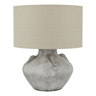 A handcrafted stone lamp with a beige shade, showcasing unique textural details and a rustic appearance.