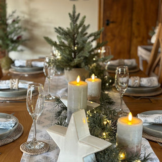 Decorated Christmas table with candles, star-shaped holder, and greenery.
