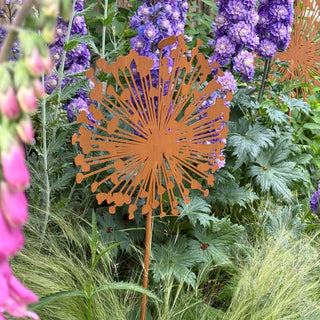 Decorative metal flower art piece among flowers and greenery
