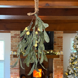 Decorative mistletoe branch with lights in a festive indoor setting.