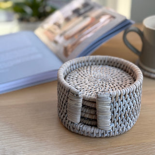 Rattan coaster set on a wooden surface with a notebook and mug in the background
