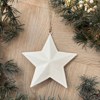 White star ornament on a wooden surface with greenery
