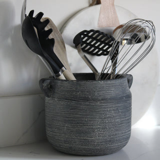 Kitchen utensils in a woven basket on a marble countertop