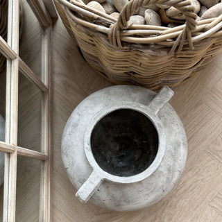 Concrete pitcher on a wooden floor with a woven basket in the background