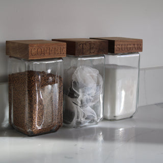 Tea coffee and sugar canisters. Glass with wood tops on marble worktop 