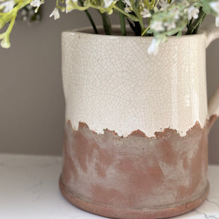 Ceramic vase with textured surface holding white flowers on a neutral background
