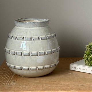 Decorative ceramic vase with lattice design on a wooden surface.