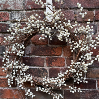 Decorative wreath with white berries against a brick wall