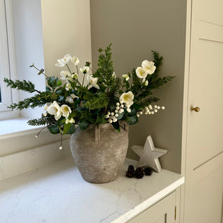 Floral arrangement in a textured vase on a white surface with a star decoration.