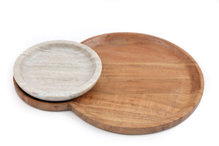 Two round serving boards, one made of marble with a white surface and the other made of wood with a natural brown finish, positioned one over the other against a white background.