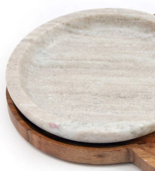 Section of two round serving boards, one made of marble with a white surface and the other made of wood with a natural brown finish, positioned one over the other against a white background.
