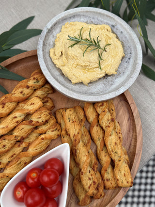 Dip with herbs in a bowl on a wooden  and marble board with bread sticks and cherry tomatoes.