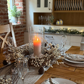 Dining table set with candles, glasses, and decorative elements in a cozy kitchen.