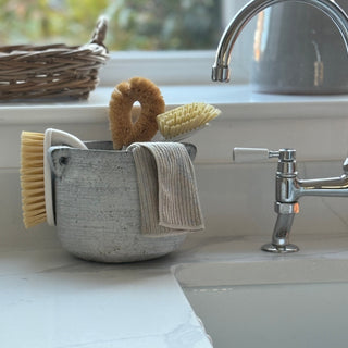 Kitchen sink area with a basket containing cleaning supplies and a towel.