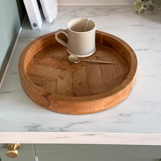 Wooden tray with a ceramic mug and spoon on a marble countertop.