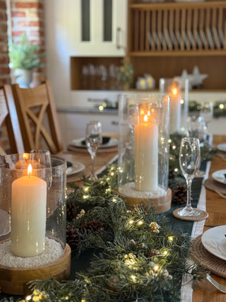 Decorative table setting with candles and greenery in a kitchen.