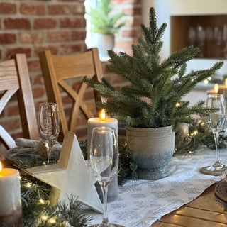 Decorated Christmas table with candles, glasses, and a small tree.