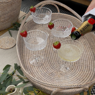 Wicker table with glasses and a bottle on a patterned rug