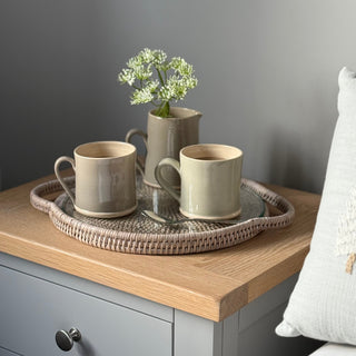 round rattan tray with glass on bedside table with cups on 