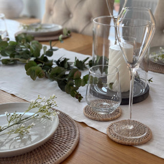 round rattan coasters styled on table with glass ware and candles 