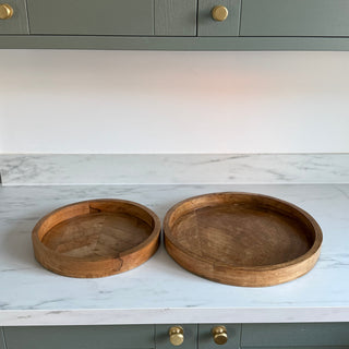 Two wooden trays on a marble countertop with green cabinets in the background.