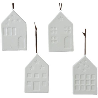 Set of four white ceramic house-shaped ornaments hanging on twigs against a white background