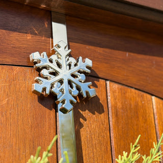Metallic snowflake-shaped door knocker on a wooden door