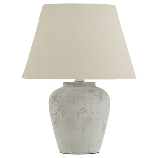 A beige stone lamp with a rustic finish and a linen shade, handcrafted and displayed against a white background.