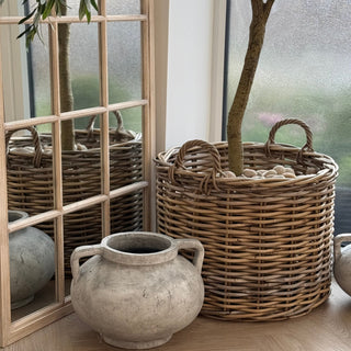 Wicker basket with plant and decorative vase on a wooden floor
