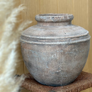 Vintage-style terracotta pot on a wooden surface with a neutral background