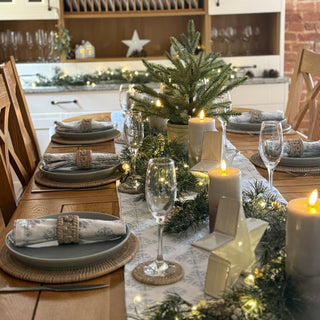 Decorated Christmas table with greenery, candles, and glasses in a kitchen setting.