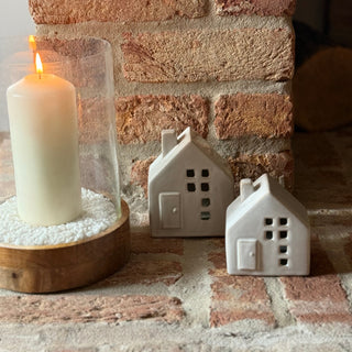 Candle and ceramic house-shaped lamps on a brick surface