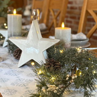 Decorative star and candles on a table with a brick wall background