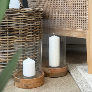 Two wooden side tables with white candles on a wooden floor.