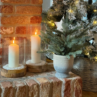 Decorative setup with candles and a Christmas tree against a brick wall.