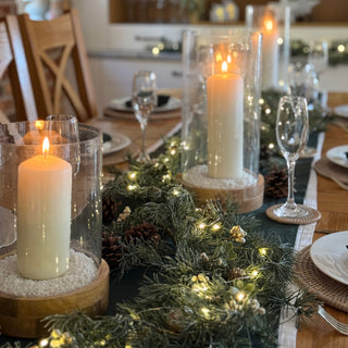 Decorative table setting with candles and greenery.