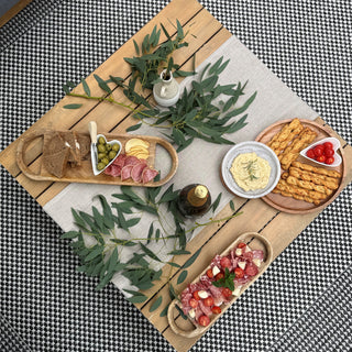 Wooden platter with assorted snacks and appetizers on a checkered tablecloth