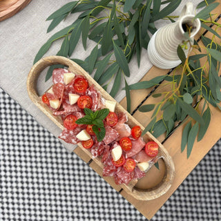 Platter of antipasto with tomatoes and salami on a checkered tablecloth